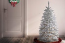 a prelit christmas tree near a door