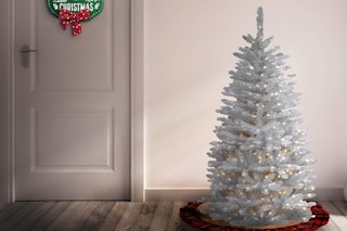 a prelit christmas tree near a door