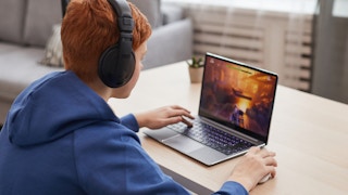 A teenager playing a video game on a laptop.
