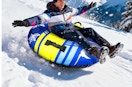 a person on a snow tube going down a snowy hill