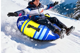 a person on a snow tube going down a snowy hill