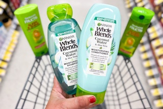 hand holding two bottles of garnier in front of two bottles balancing on edge of shopping cart