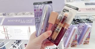 Someone holding up some makeup in the makeup section of a store
