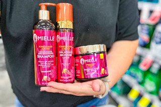 person holding mielle shampoo, gel, and mousse