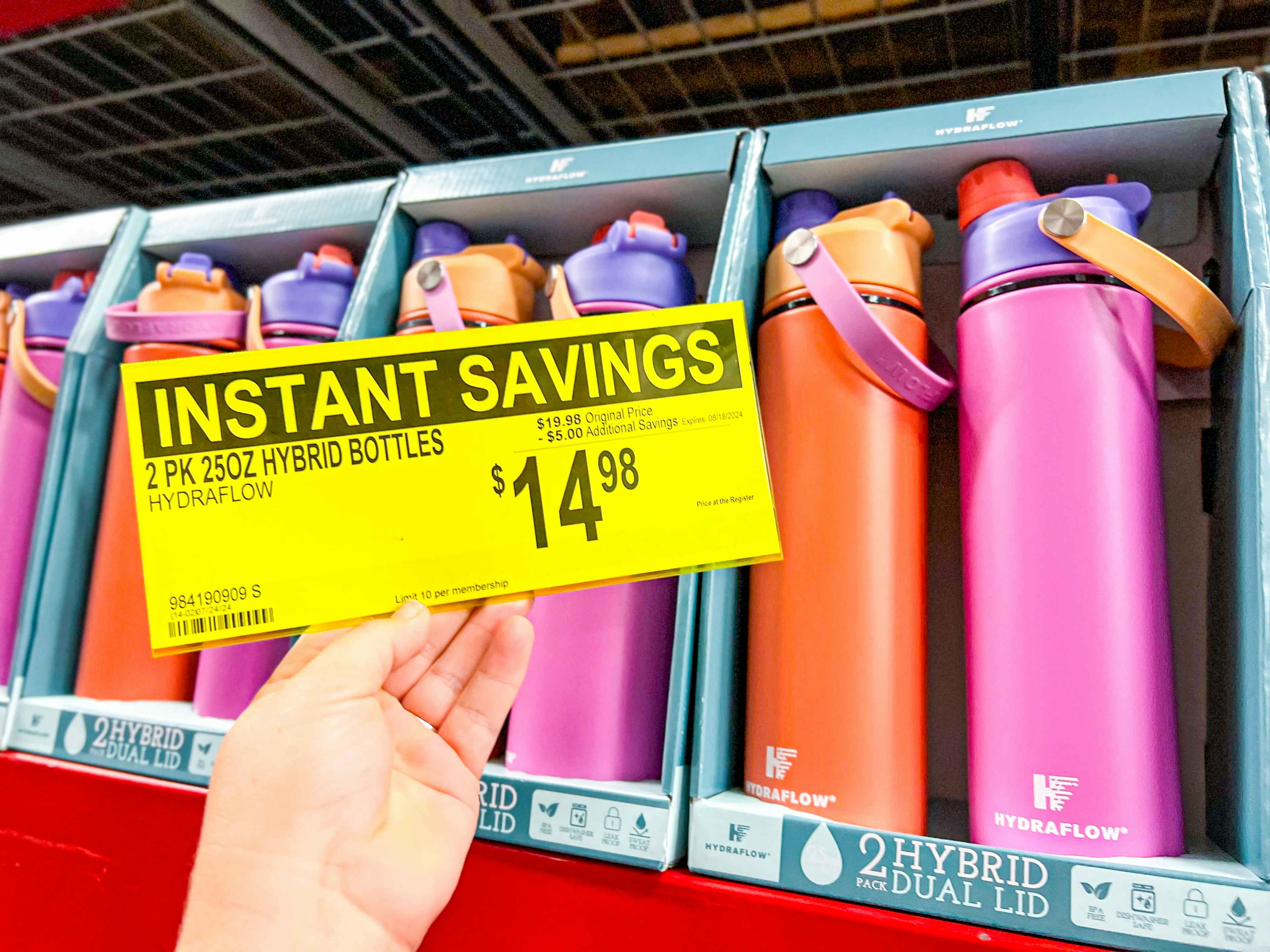 person holding a sign for $14.98 in front of water bottles