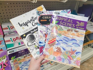 hand holding 3 adult coloring books