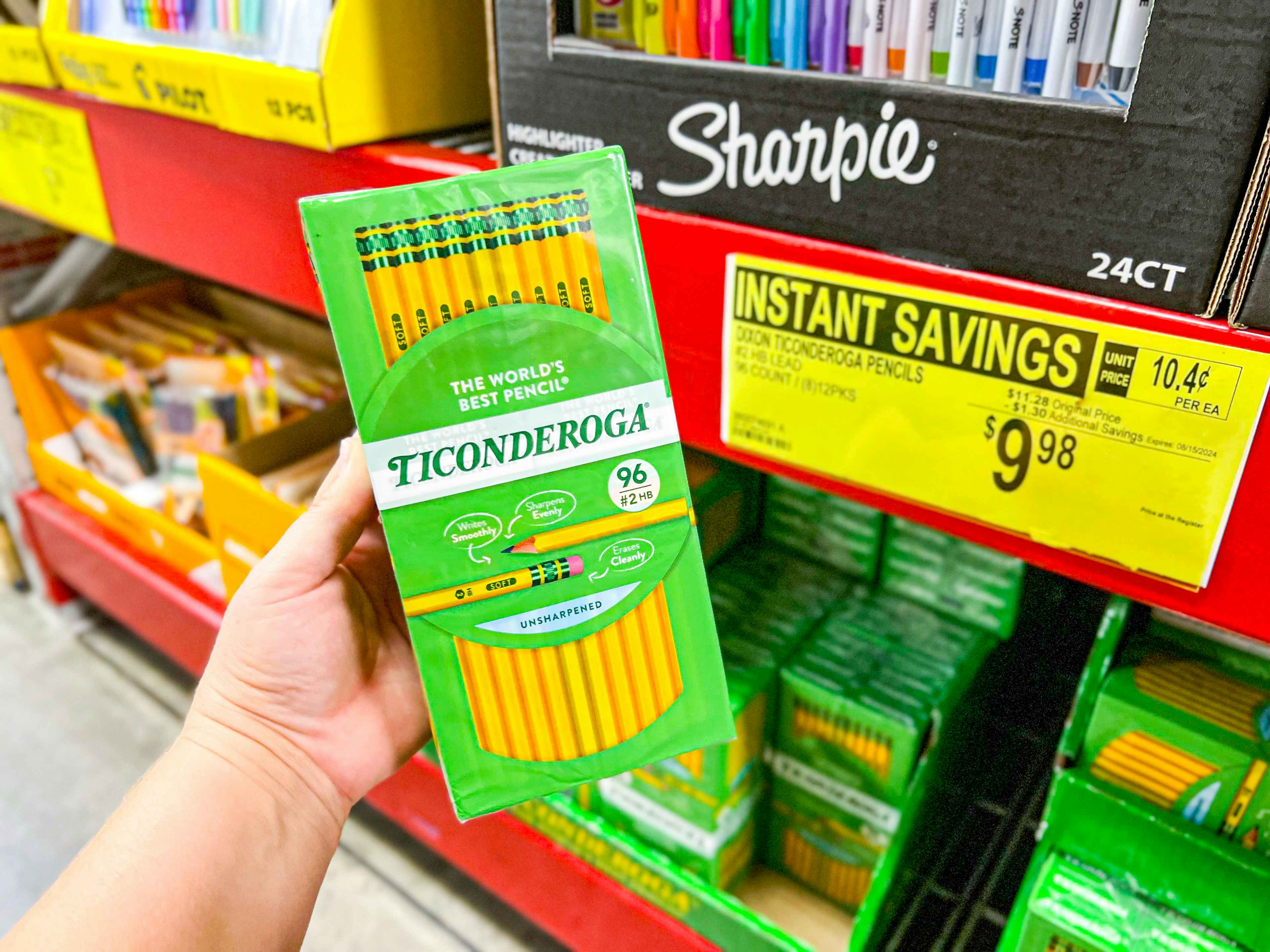 person holding a pack of ticonderoga pencils by a sign for $9.98