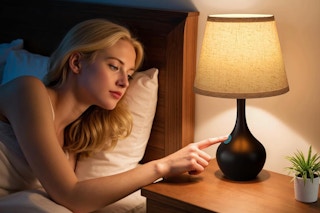 woman turning on lamp from her bedside