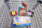 strawberries, hawaiian rolls, mushrooms, and chicken drumsticks in a cart