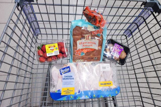 strawberries, hawaiian rolls, mushrooms, and chicken drumsticks in a cart