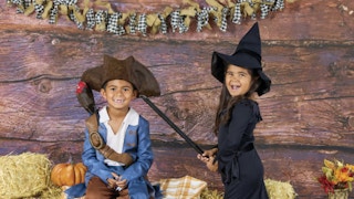 two children in costume in front of a fall backdrop