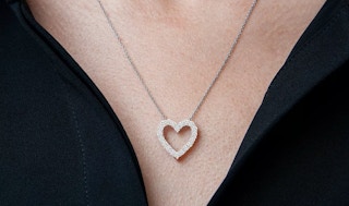 a woman wearing a diamond heart necklace