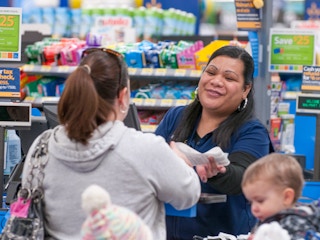 A Walmart employee handing receipt to a customer at the checkout counter.