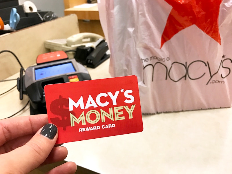 hand holding Macy's Money card at checkout with bag