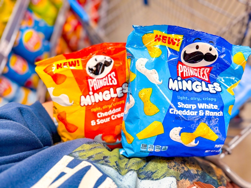 person holding two bags of pringles mingles over walmart cart