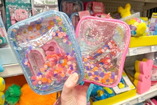 hand holding two pink and blue kids gift sets in a store's easter aisle