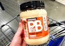 a hand holding a container of peanut butter powder