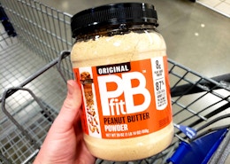 a hand holding a container of peanut butter powder