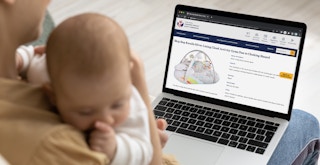 A mom holding her baby, looking at the CPSC website page about the recall of the Skip Hop Silver Linings Cloud Baby Gym