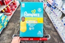 person pushing a cart with pampers swaddlers diapers in it