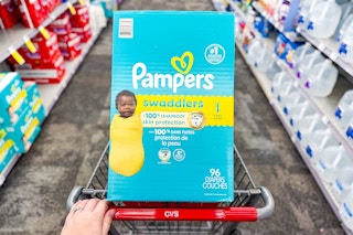person pushing a cart with pampers swaddlers diapers in it