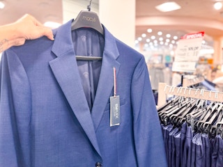 hand holding up suit jacket on a hanger