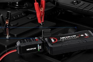 A Nexpow automobile jump starter is connected to the battery of a car.