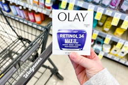 person holding an olay moisturizer over a walgreens cart