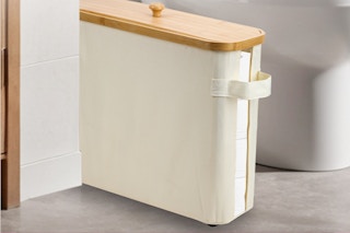 A cream toilet paper storage box with a wood-grain lid and a side handle sits next to a toilet, taking up not much space.