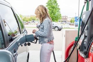 A person filling their vehicle with gas at a gas station pump.