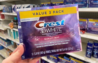 hand holding crest 3d white toothpaste 3-pack