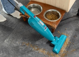 a blue small vacuum vacuuming a rug