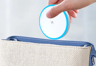a hand putting a wireless charger circle in a bag