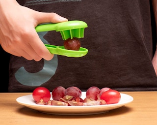 Someone cutting up grapes with a cutter