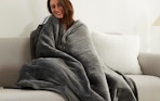 A woman wearing a blanket while sitting on a couch.