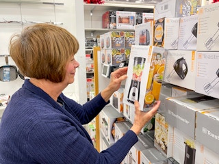A woman looking at small kitchen appliances inside Kohl's.