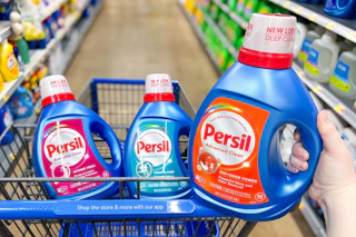 hand holding the blue and orange Persil bottle with a pink and light blue label in the Walmart cart