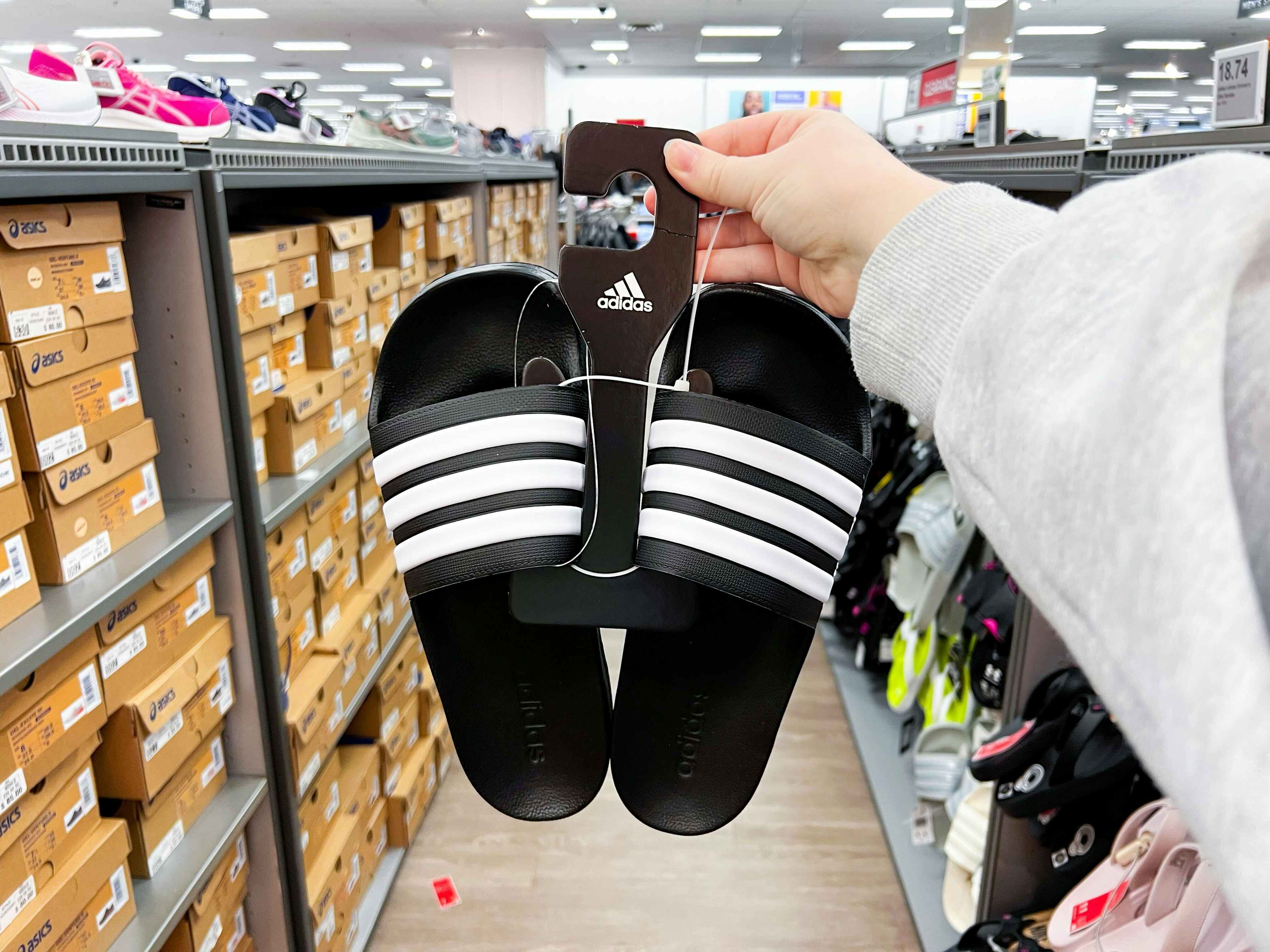 adidas slides held up infront of shoe display in store
