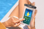 someone holding a waterproof phone pouch next to a pool