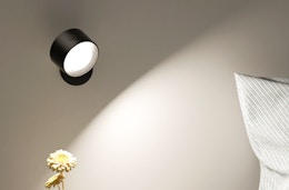 a wall light shining on a pillow and flower