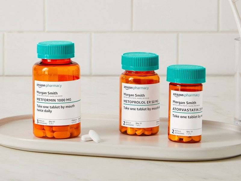 Three Amazon Pharmacy Rx pill bottles sitting on a tray on a bathroom counter.