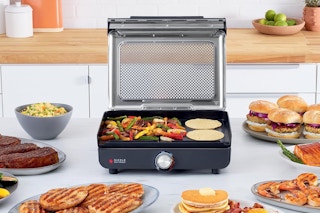 Ninja Indoor Grill & Griddle on a kitchen counter surrounded by food