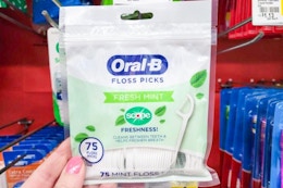 hand holding a pack of oral b floss picks at dollar general