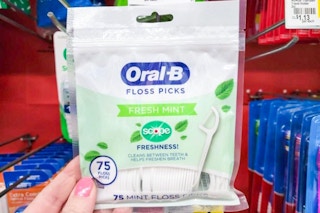 hand holding a pack of oral b floss picks at dollar general