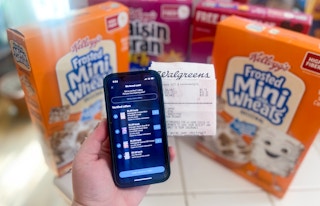 hand holding a phone with Ibotta rebates and a walgreens receipt in front of kelloggs cereal boxes