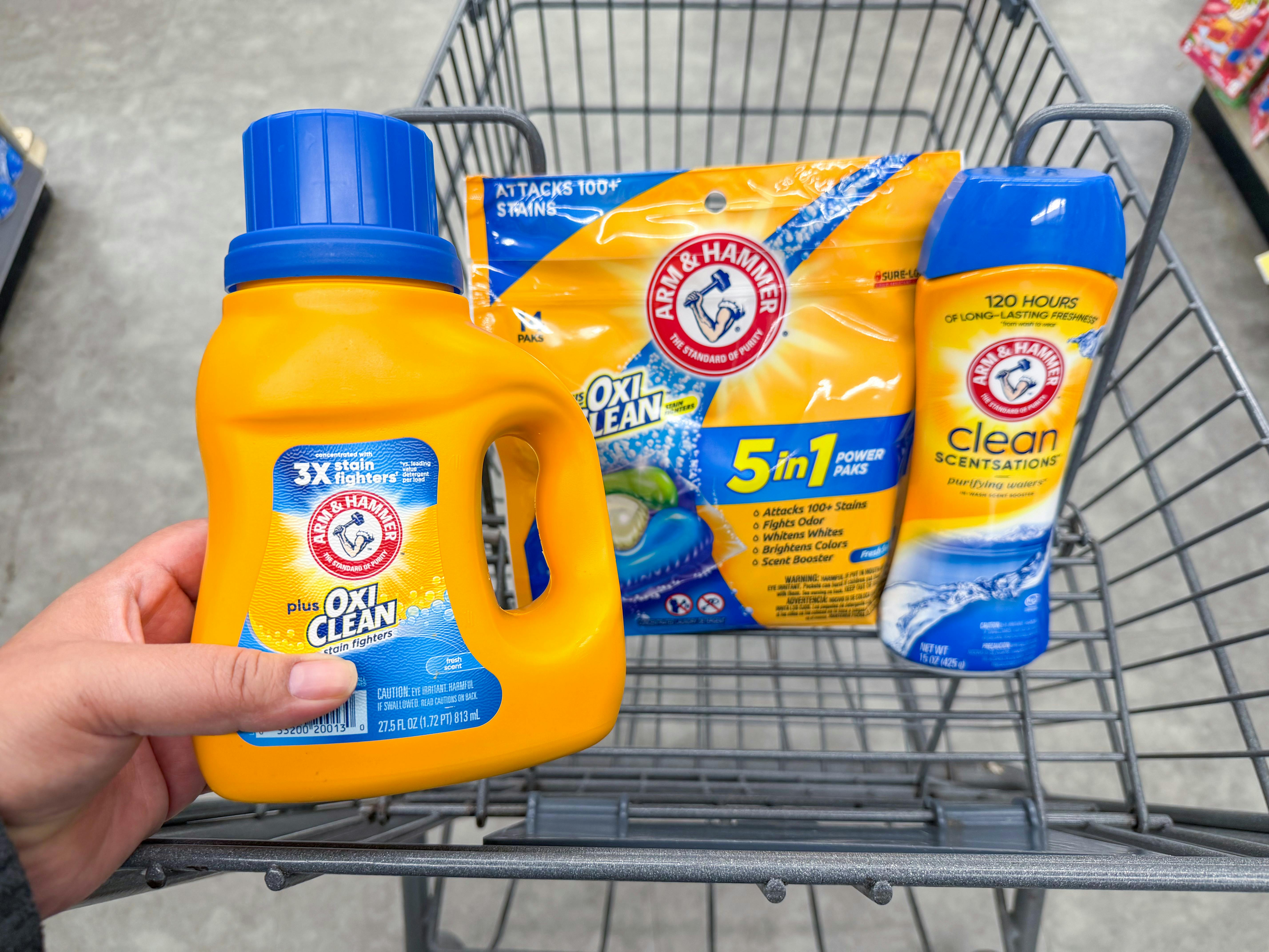 hand holding arm & hammer detergent and laundry products in walgreens cart
