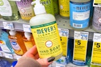 person holding a mrs meyers hand soap bottle