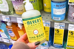 person holding a mrs meyers hand soap bottle