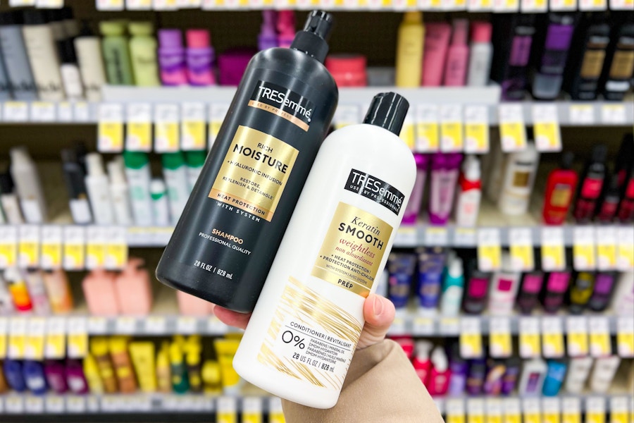 person holding tresemme shampoo and conditioner in front of a display of hair care