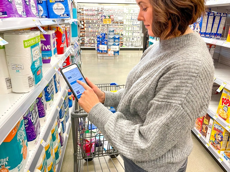 woman pointing at coupon on cell phone in walgreens